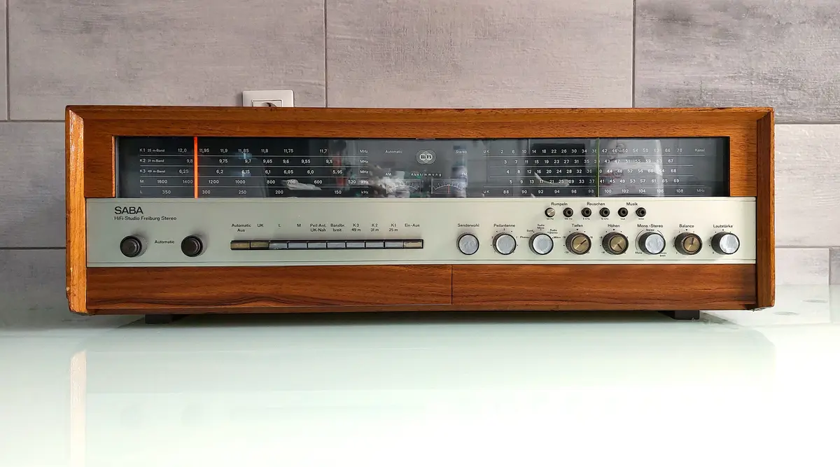 A vintage SABA HiFi-Studio Freiburg Stereo radio receiver with a wooden casing and numerous dials and switches, sitting on a…