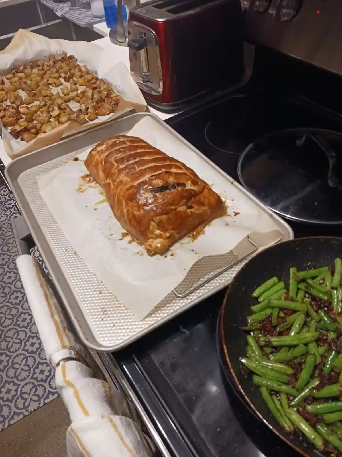 A kitchen scene shows a golden-brown, baked meatloaf in a loaf pan, surrounded by roasted potatoes and green beans. The text…
