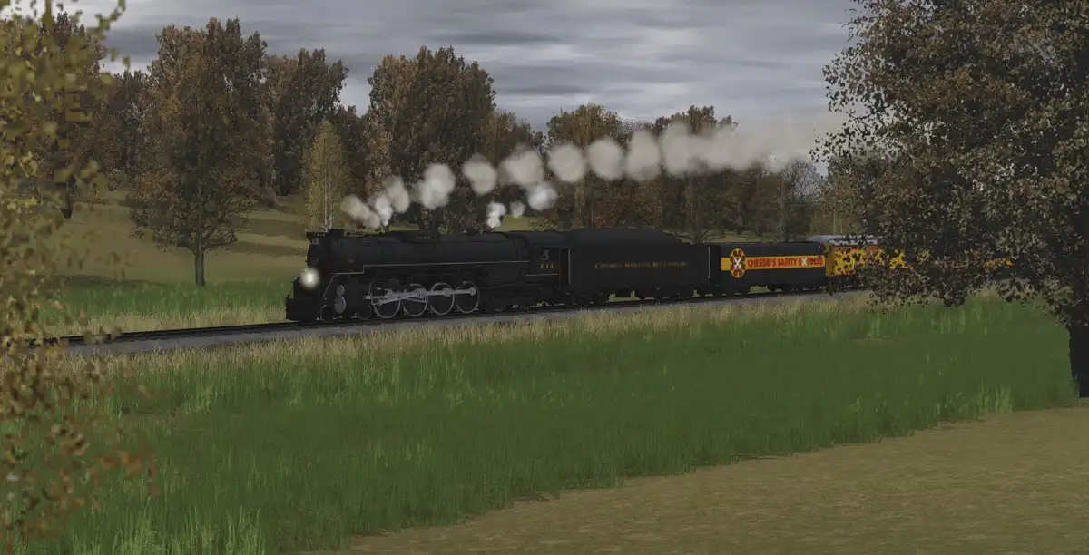 A black steam locomotive with 'Chessie System Railroads' written on its side is pulling a train through a grassy, wooded…