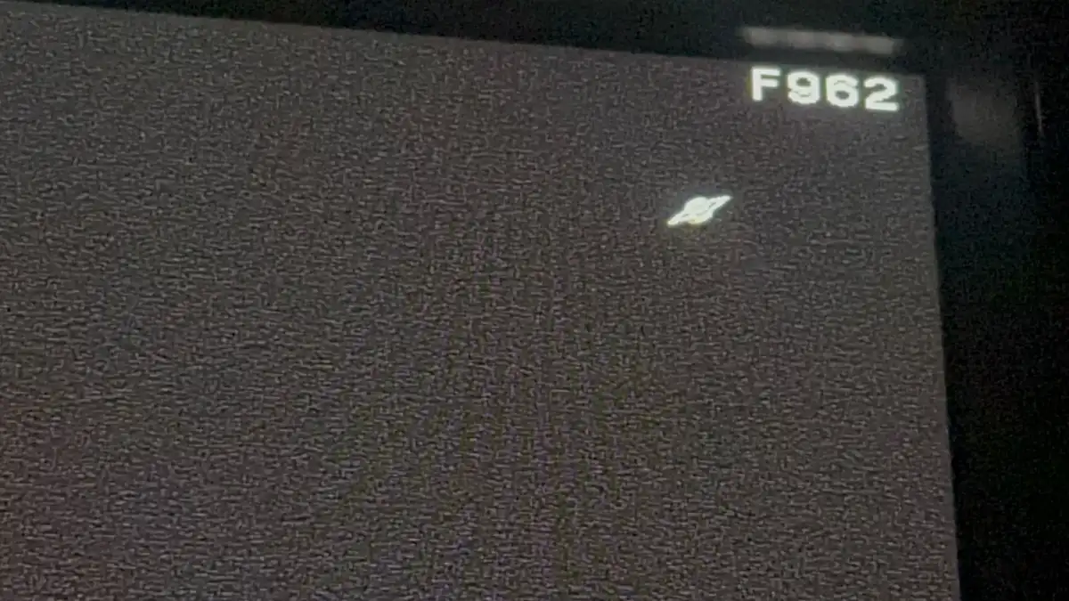 A grainy, static-filled screen shows a small, blurry image of a Saturn-like planet with rings, positioned near the top right…