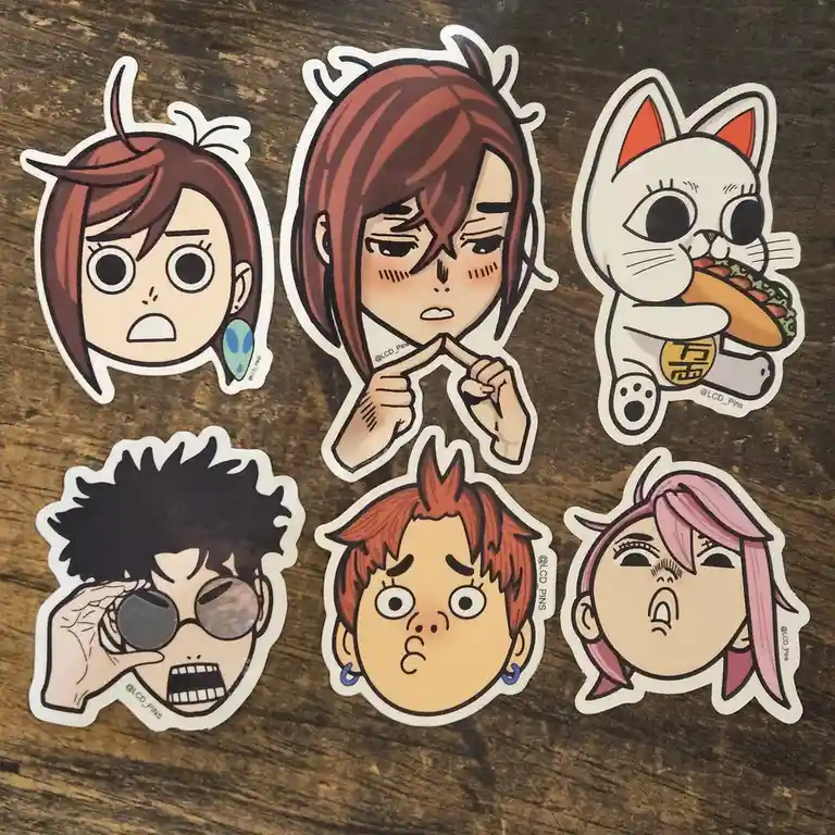 Six anime-style character stickers are arranged on a wooden surface, depicting various exaggerated facial expressions: a…