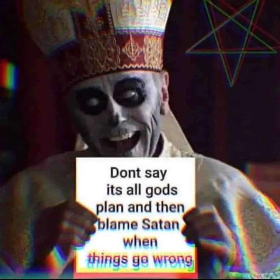 A person dressed as a skeletal, smiling priest wearing a colorful ornate mitre and holding a sign with the text 'Dont say…