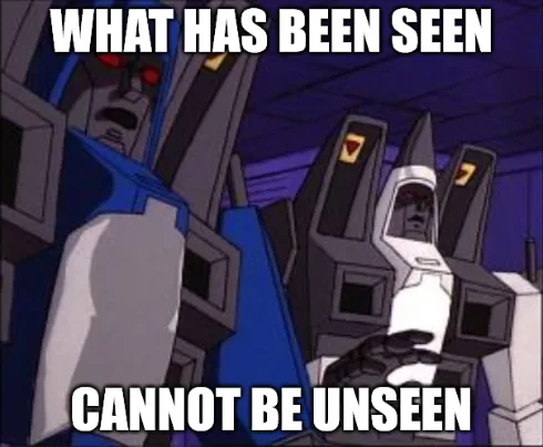 Two animated robot characters from the Transformers cartoon, one blue and one white, stare intensely at the viewer. The blue…
