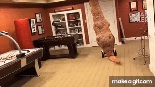 A cat wearing a dinosaur costume is shown in a sequence of six frames falling over in a game room. The cat starts upright…