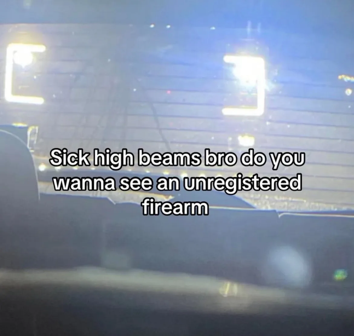 A blurry nighttime photo taken from inside a car, showing the bright, glaring high beams of another vehicle directly ahead…