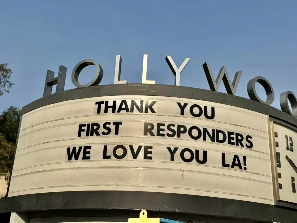 A close-up photo of the iconic Hollywood sign with a large marquee below it displaying the message 'THANK YOU FIRST…