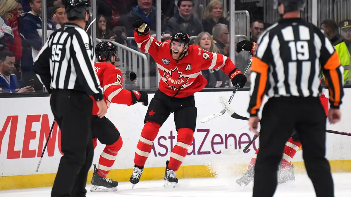 A Canadian ice hockey player in a red jersey with a maple leaf and the number 9, celebrating exuberantly with one arm raised…
