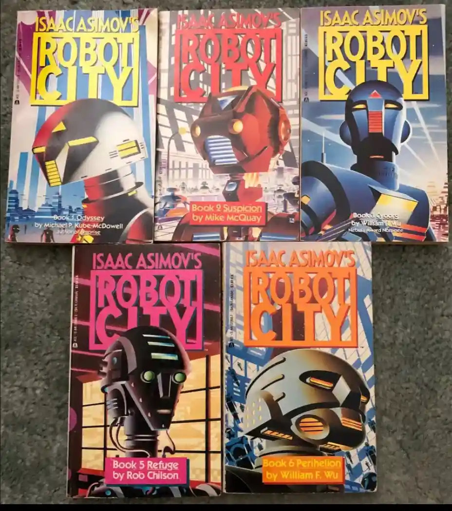 Five paperback books titled 'Isaac Asimov's Robot City' are arranged in a fan-like spread on a gray carpet. Each cover…
