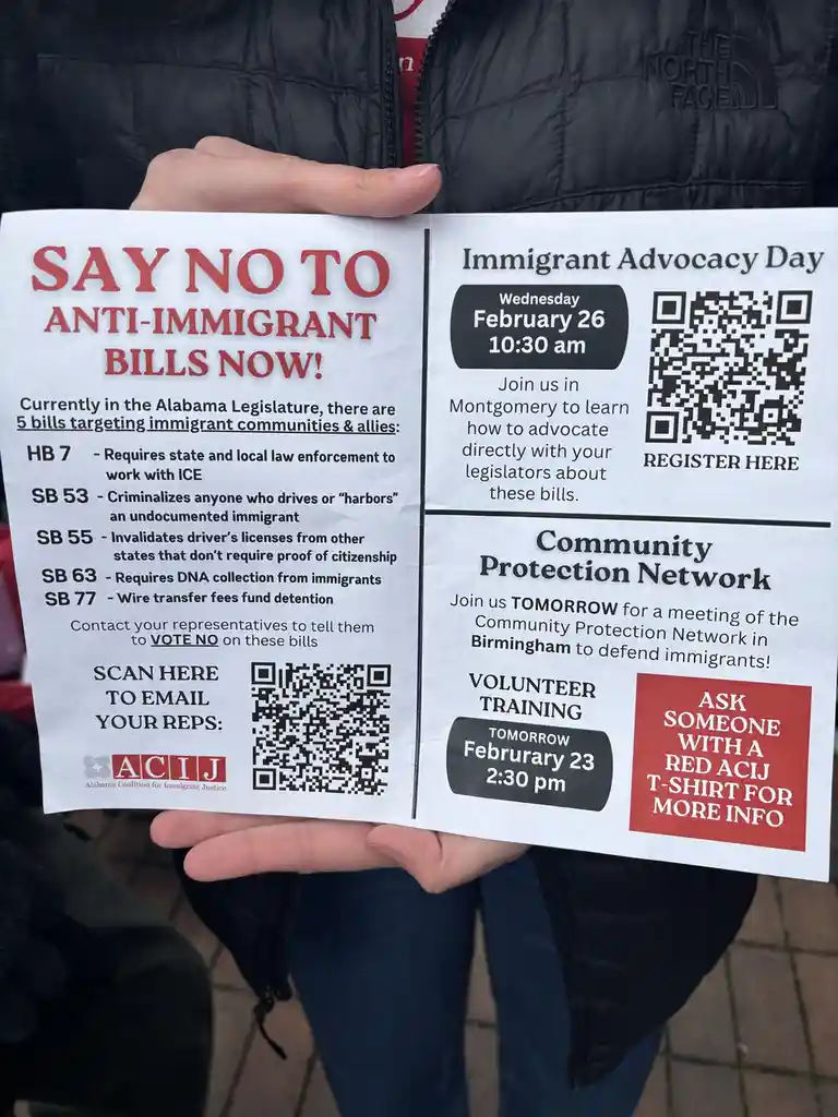 A person holds a flyer from the Alabama Coalition for Immigrant Justice (ACIJ) listing five anti-immigrant bills (HB 7, SB…