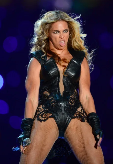 A woman with long blonde hair wearing a black leather and lace bodysuit with fishnet stockings and black gloves, holding a…