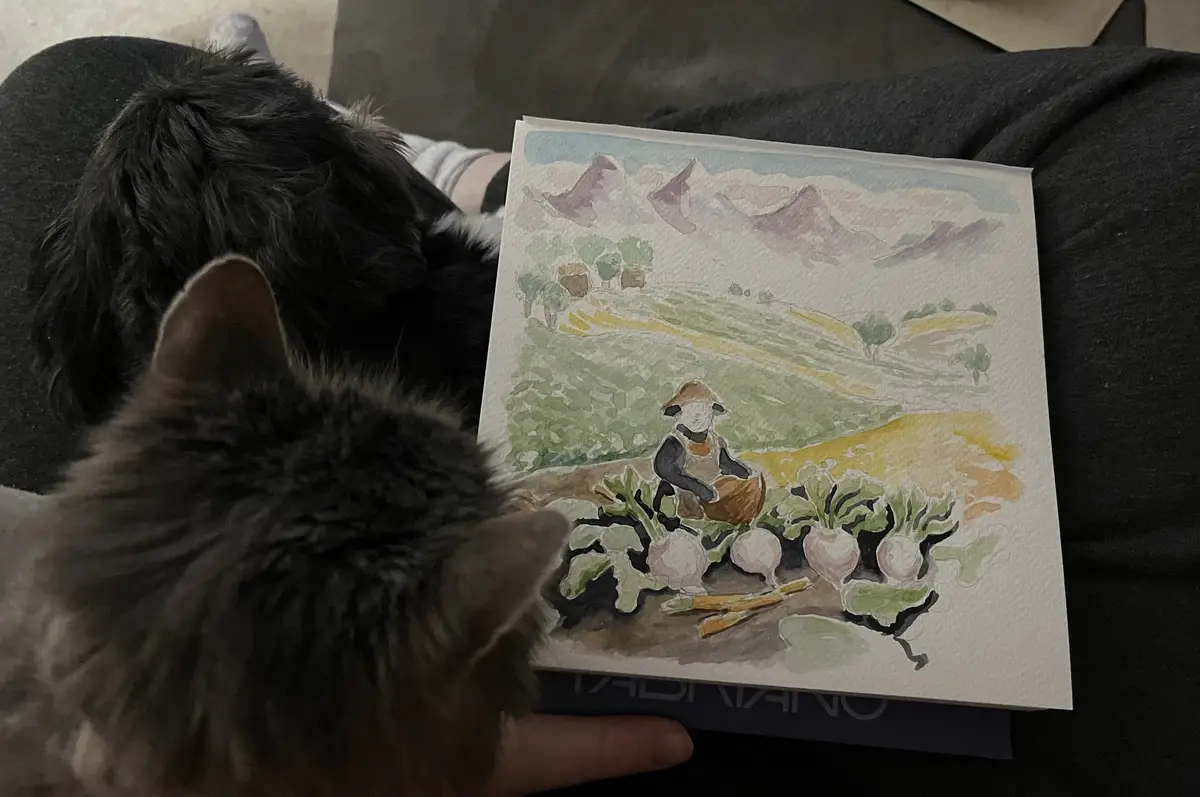 A fluffy gray cat and a black dog are looking at a watercolor painting of a farmer harvesting turnips in a mountainous…