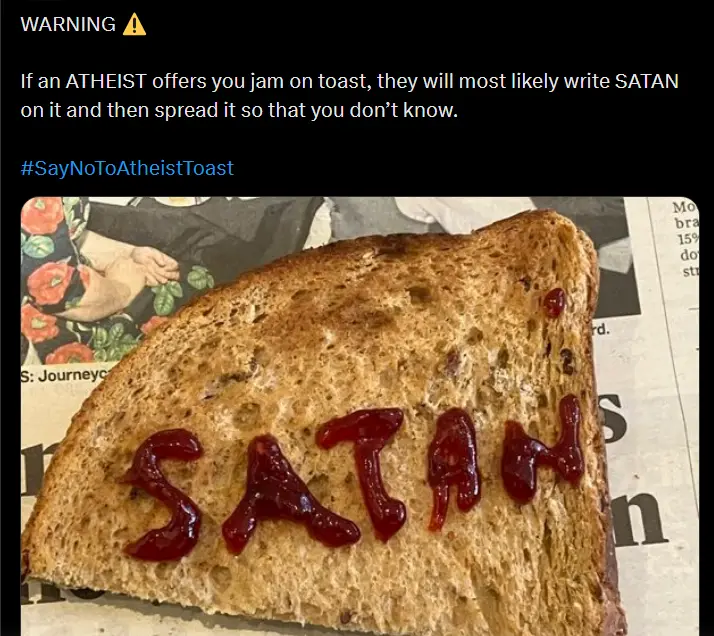 A close-up photo shows a slice of toasted bread with red jam smeared to spell out the word 'SATAN'. The image has a black…