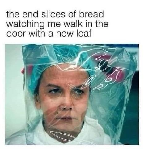 A person wearing a clear plastic face shield and a blue hairnet looks intensely at the camera with a stern expression. The…