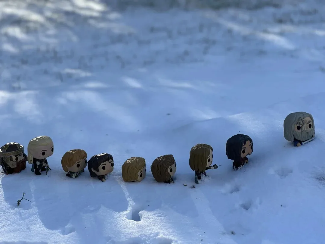 A row of Funko Pop! figures representing characters from Game of Thrones are lined up in a snowy field, with the last…