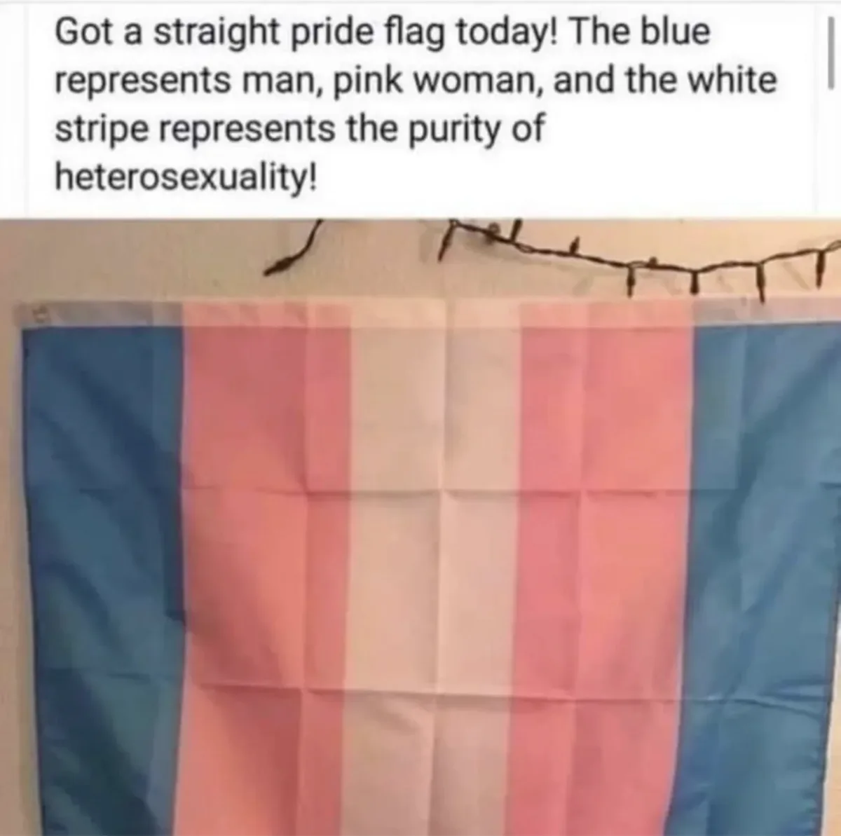 A folded flag with blue, pink, and white vertical stripes hangs on a wall beneath string lights. Overlaid text claims it's a…
