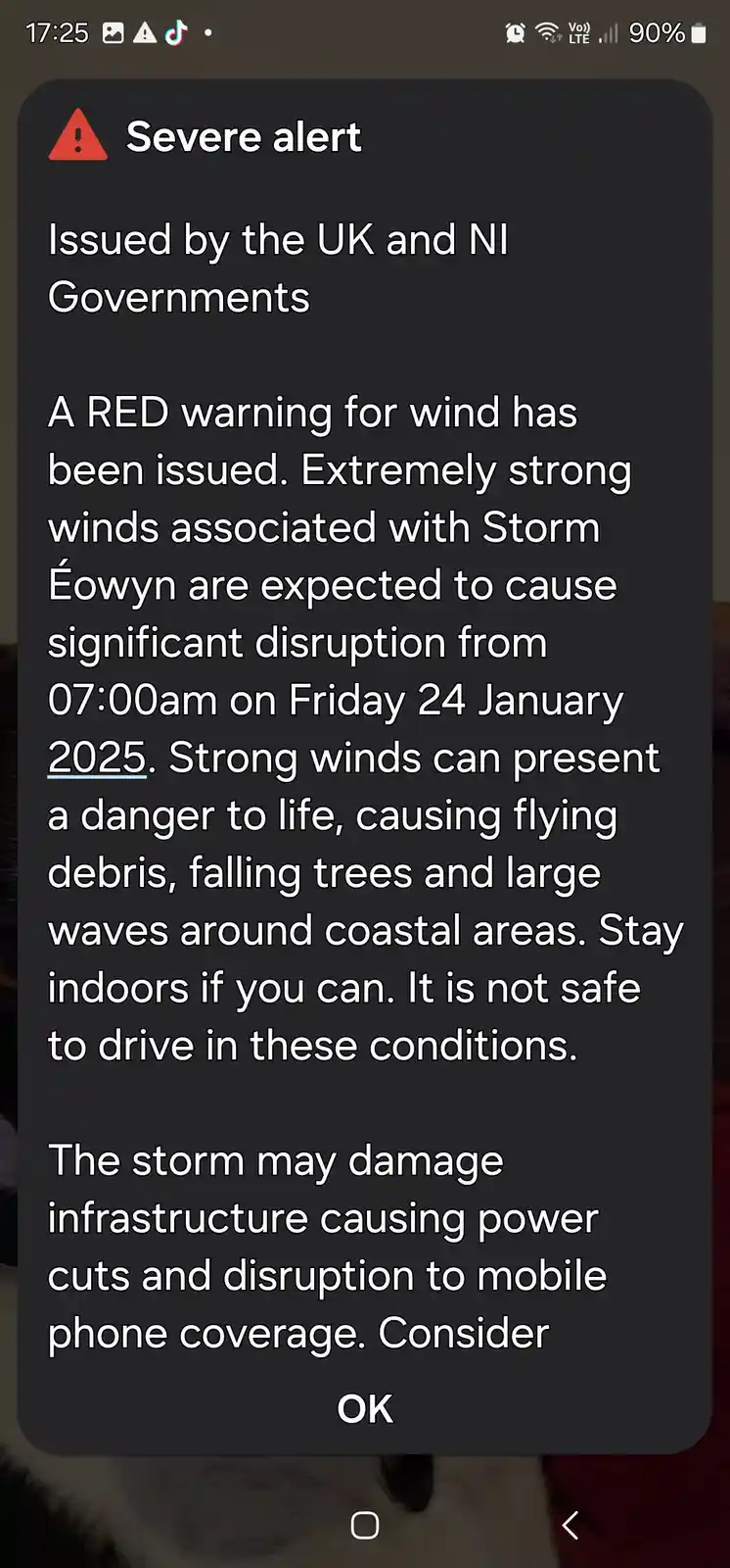 A smartphone screen displays a severe weather alert from the UK and NI Governments, warning of a red wind warning for Storm…