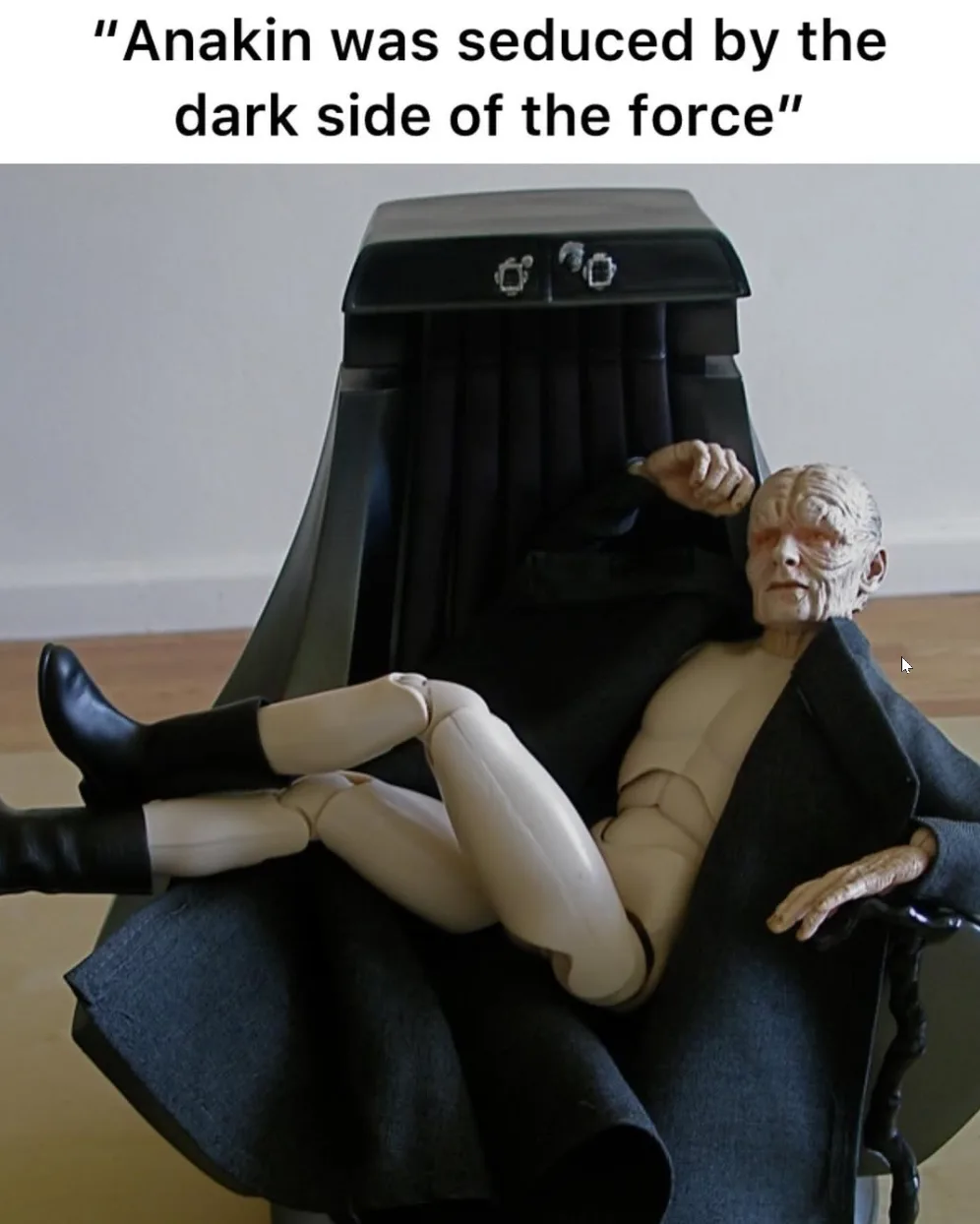 A Star Wars action figure of Emperor Palpatine reclines lazily in a black throne chair, draped in a dark robe, with his legs…