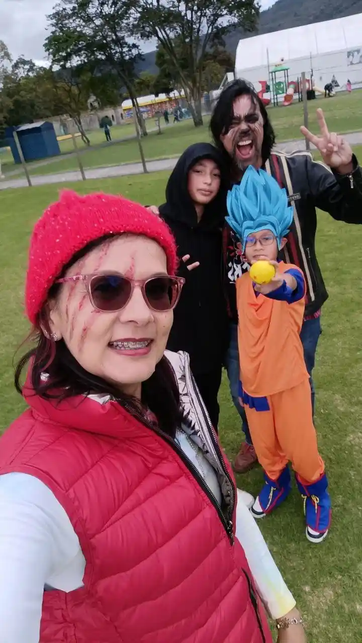 A selfie of three people outdoors, one woman in front with red face paint resembling wounds, a man behind her with dark face…