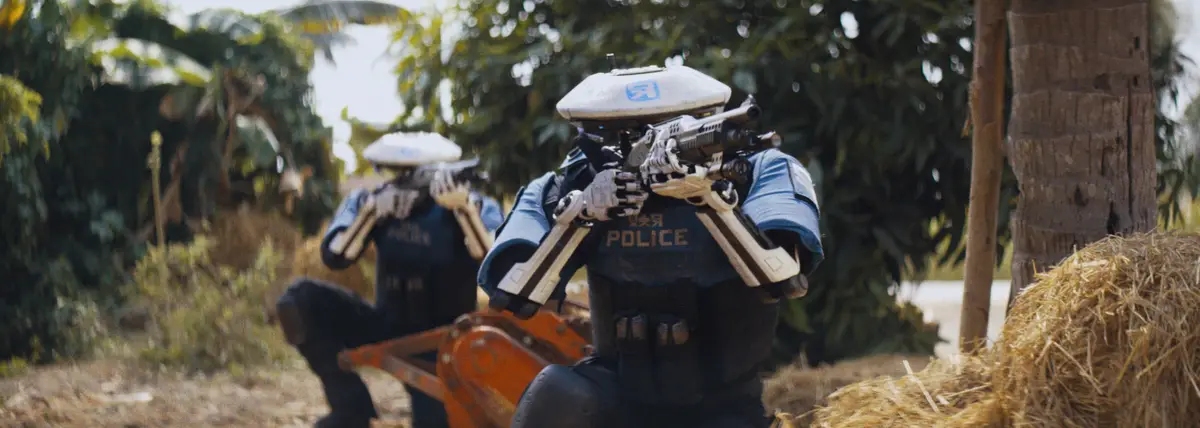 Two robotic police officers in futuristic armor are crouched in a field, aiming their weapons. The officer in the foreground…