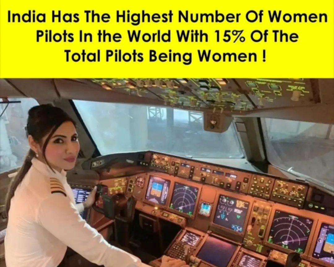 A woman in a pilot uniform sits in an airplane cockpit, smiling at the camera while her hands are on the controls. Above her…