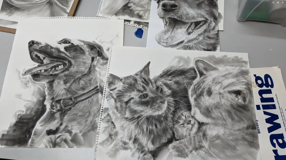 A collection of detailed pencil drawings of dogs and cats on sketch paper, with one prominent drawing of a dog with its…