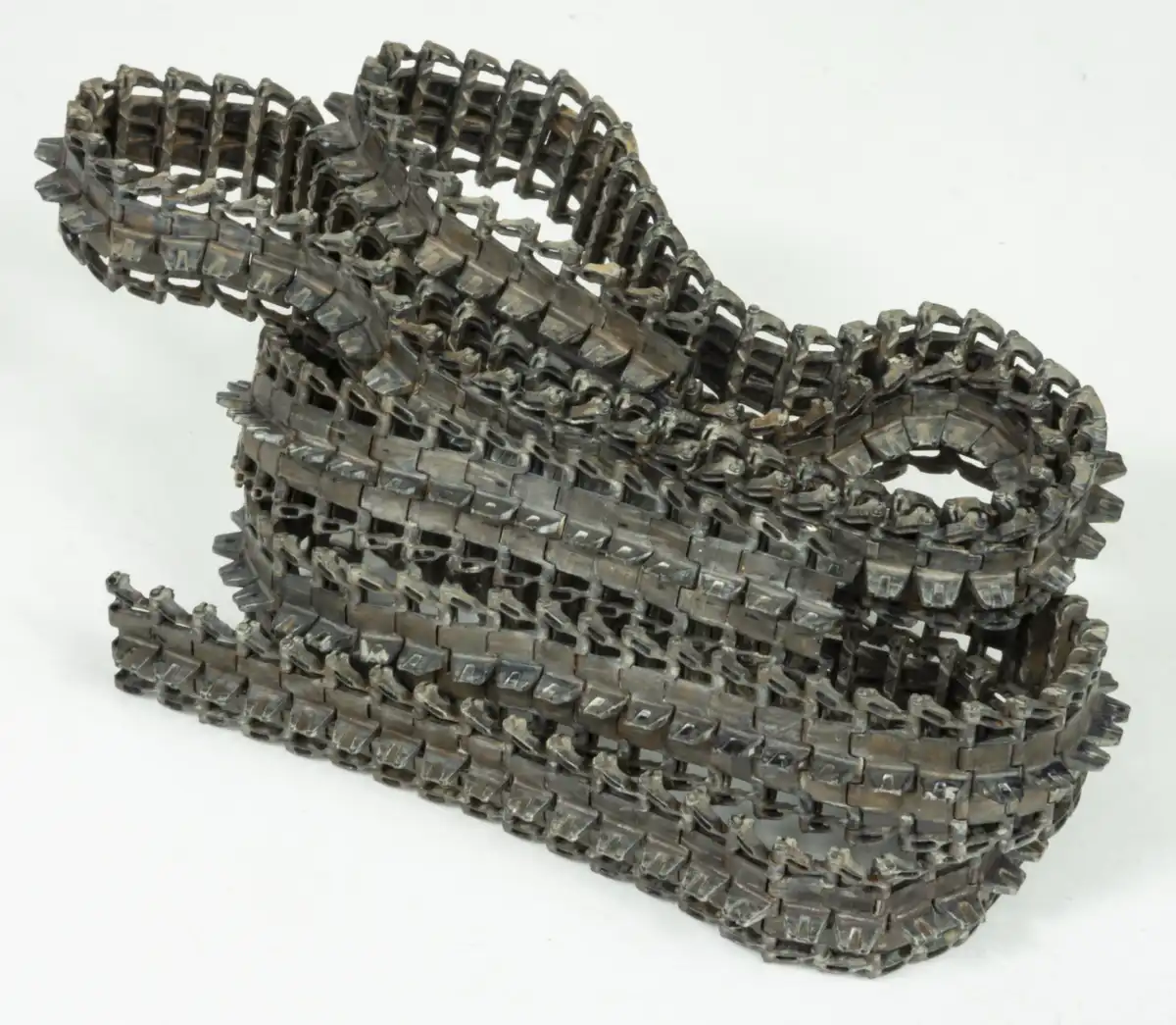 A coiled, metallic, industrial-looking chain is arranged in a tangled, abstract shape against a plain white background. The…