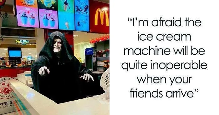 A person dressed as the dark lord from Star Wars sits behind a counter in a fast food restaurant, with ice cream menu boards…
