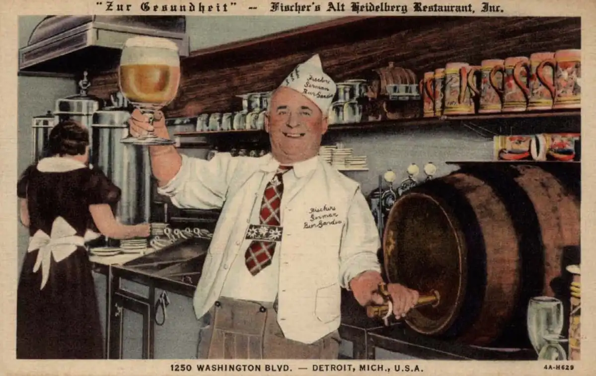 A vintage postcard depicts a cheerful German-American bartender in a white vest and hat, holding up a large beer glass while…