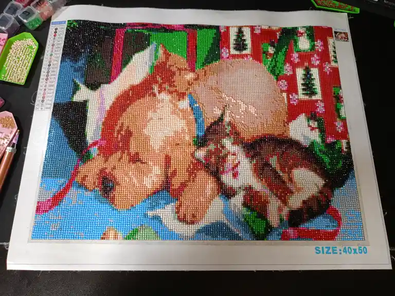A partially completed diamond painting of a cat with red hair and glasses, showing a large section of the image still blank…