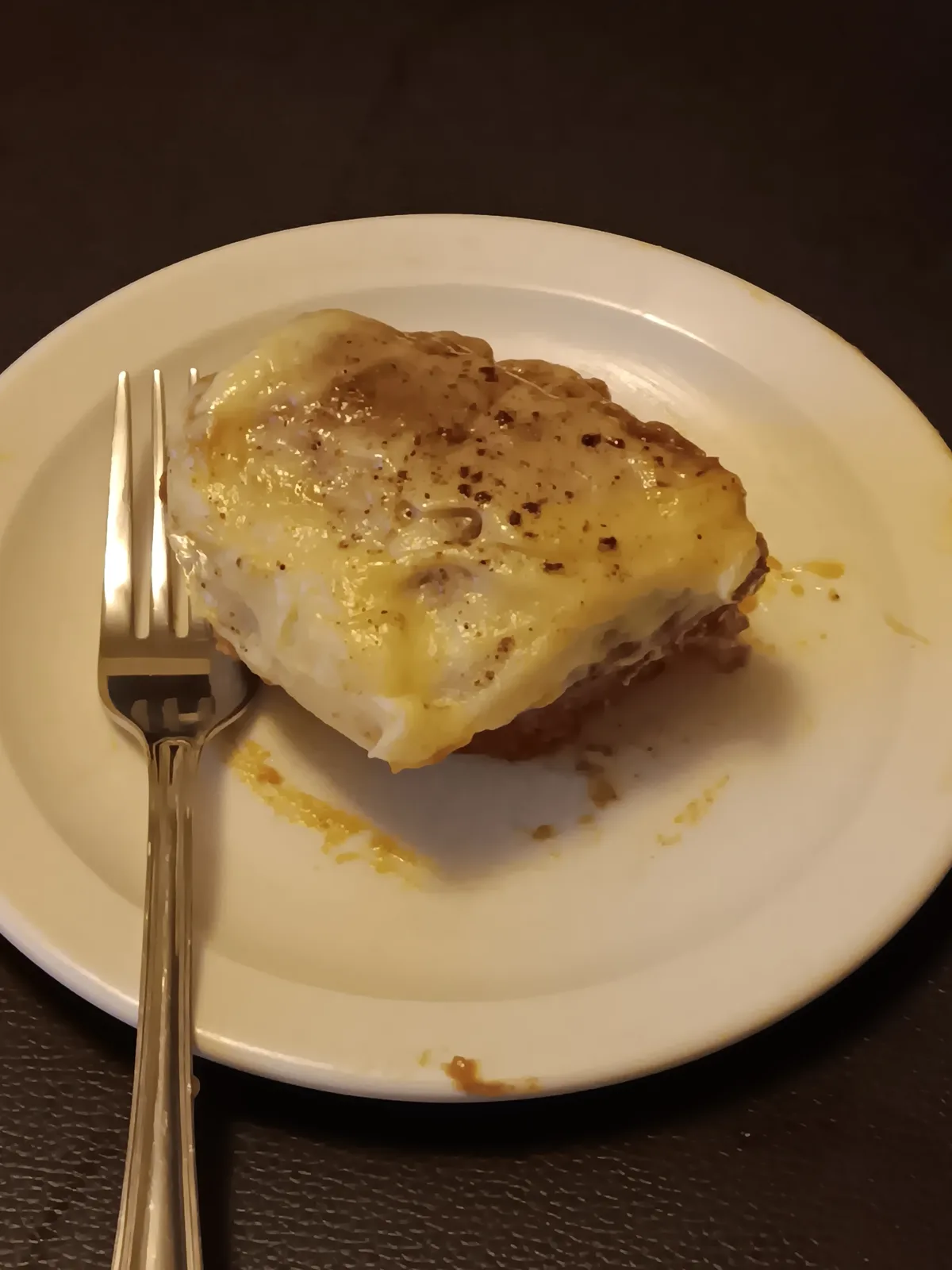 A close-up photo shows a single, square-shaped slice of what appears to be a layered dish, possibly shepherd's pie or…