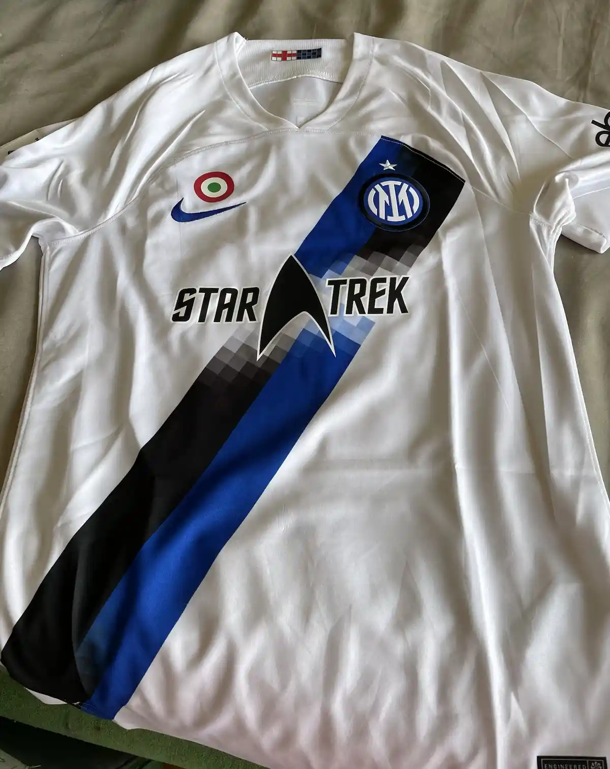 A white Inter Milan soccer jersey with a blue and black diagonal stripe, featuring the Star Trek logo and text overlaid…