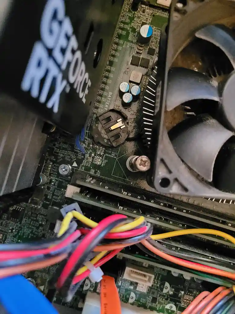 A close-up photo of the inside of a computer case showing a green motherboard with various components, a black graphics card…