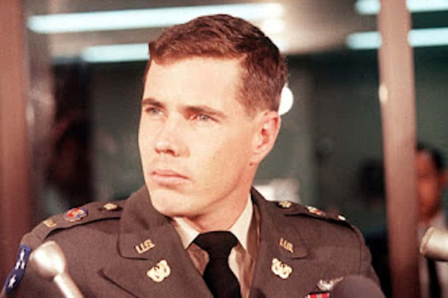 a man in a military uniform with a serious expression, surrounded by microphones, overlaid with the text 'i'm not a fan of…