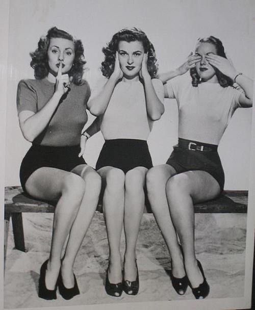 Three vintage-style women sit side-by-side on a bench, each performing a classic 'see no evil, hear no evil, speak no evil'…