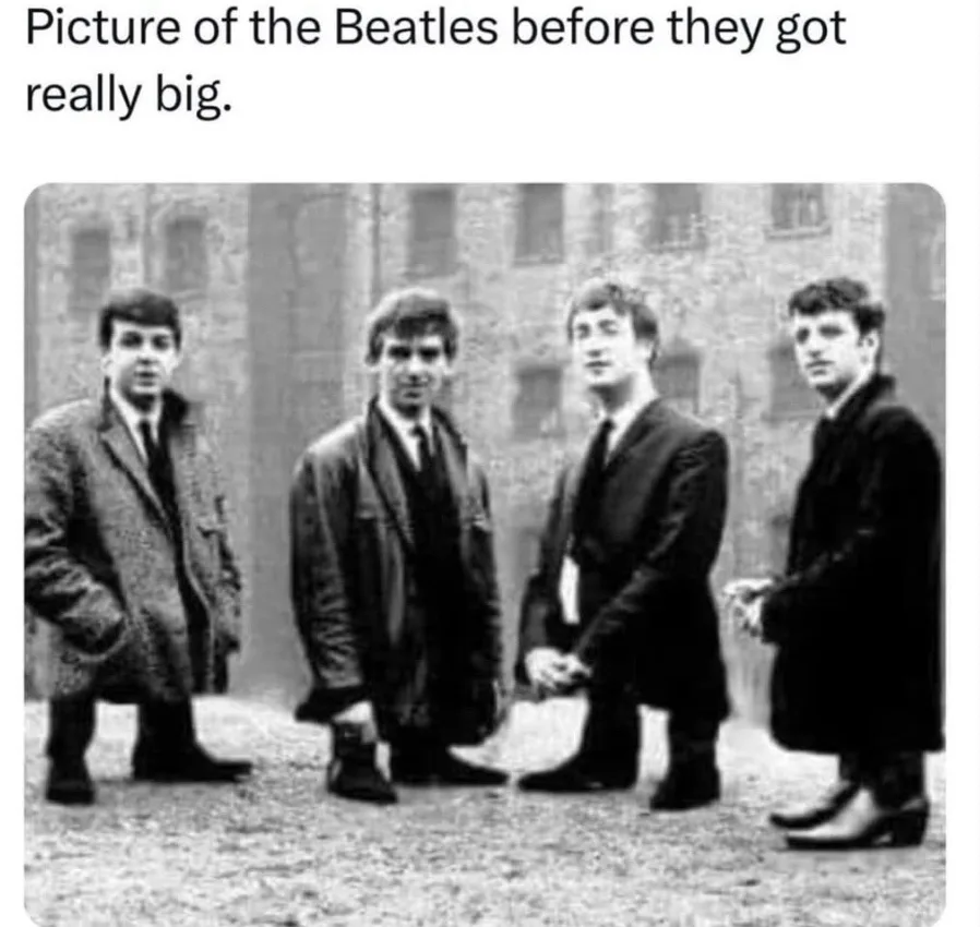 A black-and-white photograph shows four young men, later known as The Beatles, standing in a row outdoors in front of a…