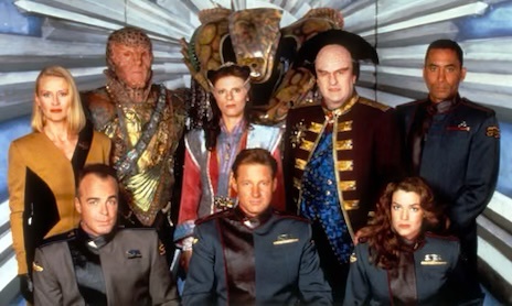 a promotional photo of the cast of 'Star Trek: Deep Space Nine' standing in front of a stylized, metallic background. The…