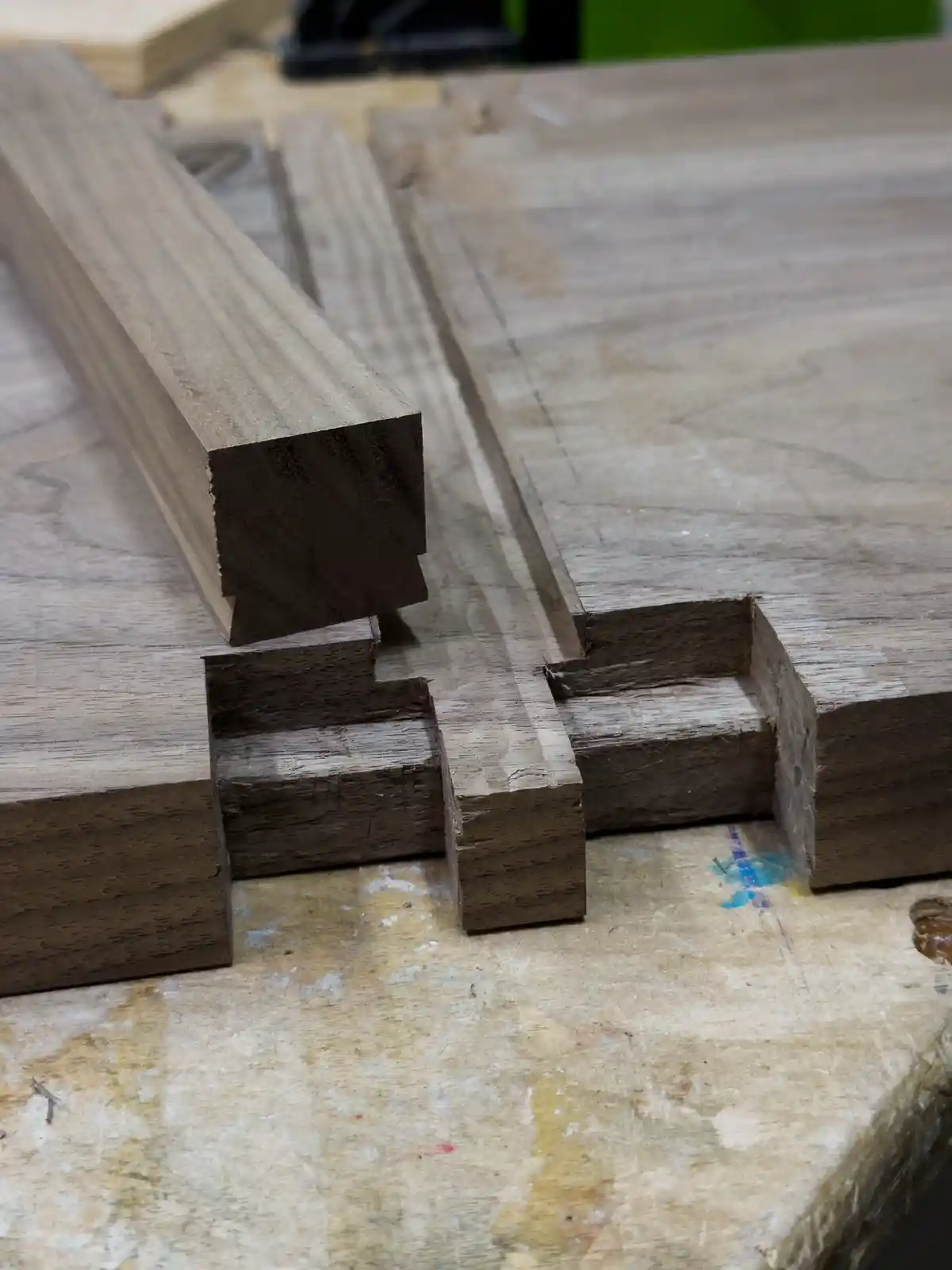 A close-up photo shows two wooden pieces with precisely cut dovetail joints on a worn workbench, with the overlaid text…