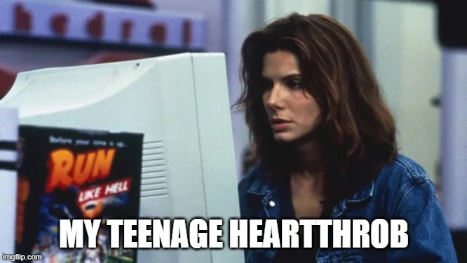 A woman with brown hair wearing a denim jacket stares intently at an old white computer monitor. A video game box labeled…