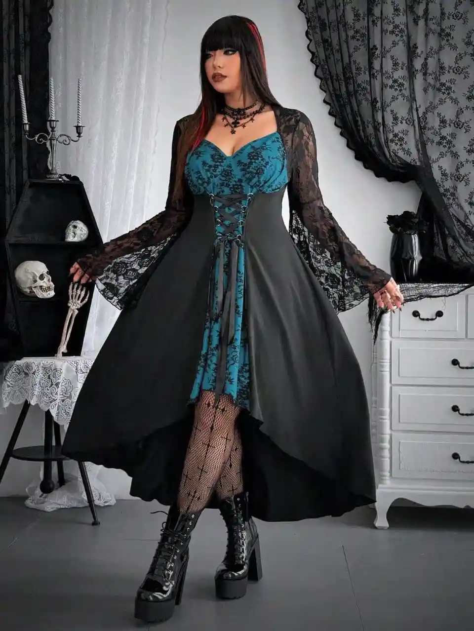 A woman in a gothic fashion outfit stands in a room decorated with skulls and black lace curtains. She wears a teal lace…