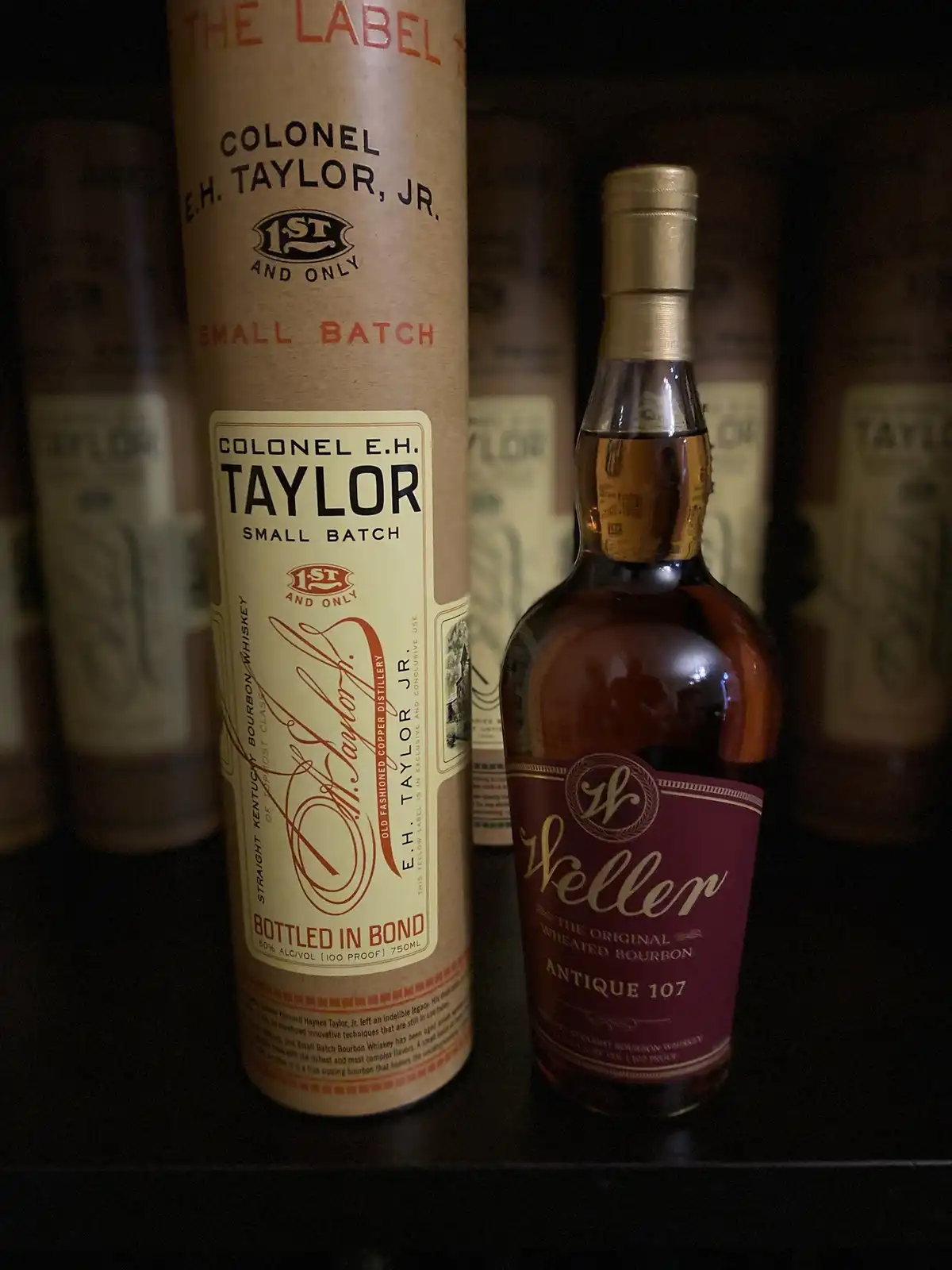 A close-up photo shows a bottle of Weller Antique 107 bourbon next to its cardboard tube packaging for Colonel E.H. Taylor…