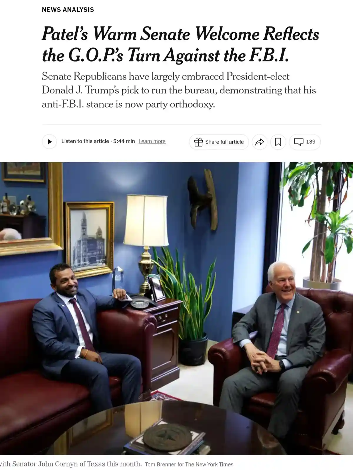 A screenshot of a New York Times article shows two men in suits smiling while seated in red leather chairs in an office with…