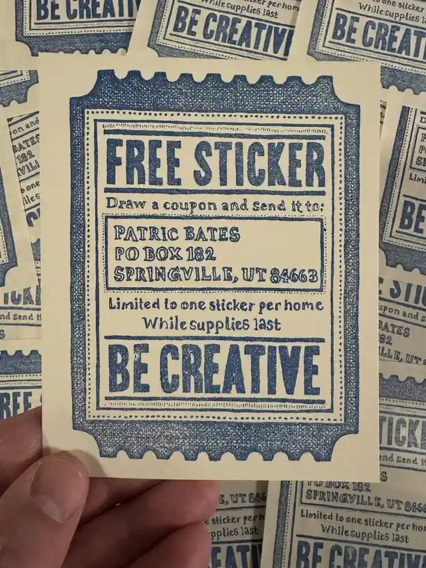 A hand holds a vintage-style, blue ink-printed sticker coupon on cream-colored paper. The coupon reads 'FREE STICKER'…