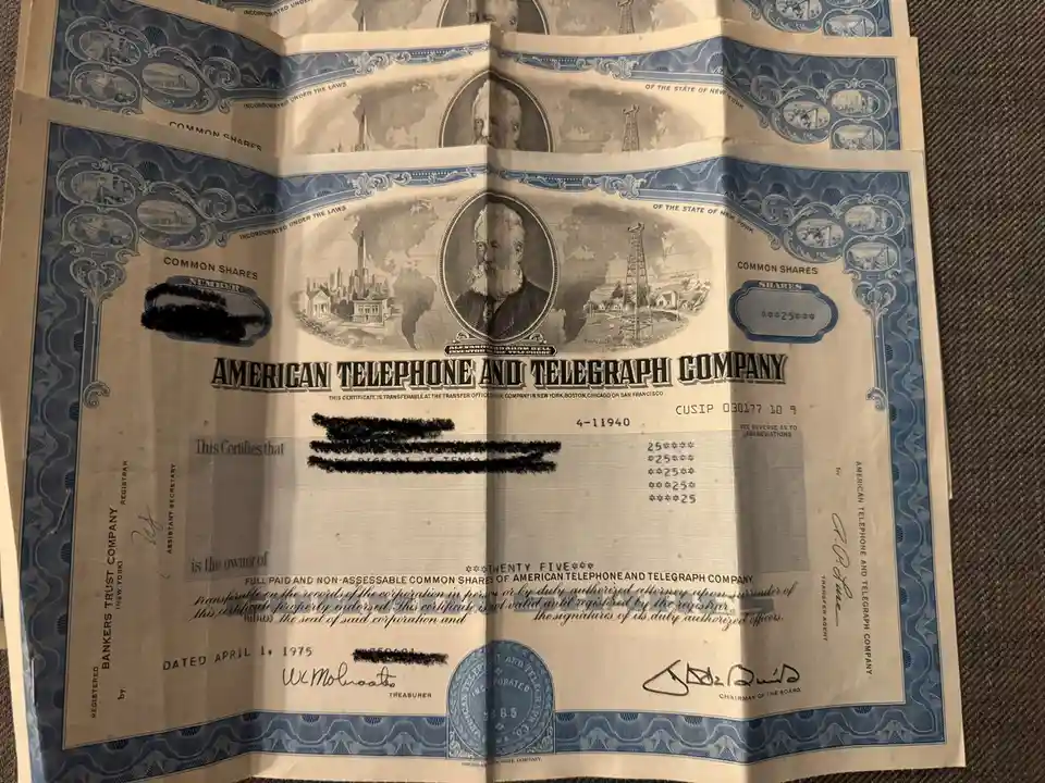 An old, ornate American Telephone and Telegraph Company stock certificate from April 1, 1975, featuring a portrait of…