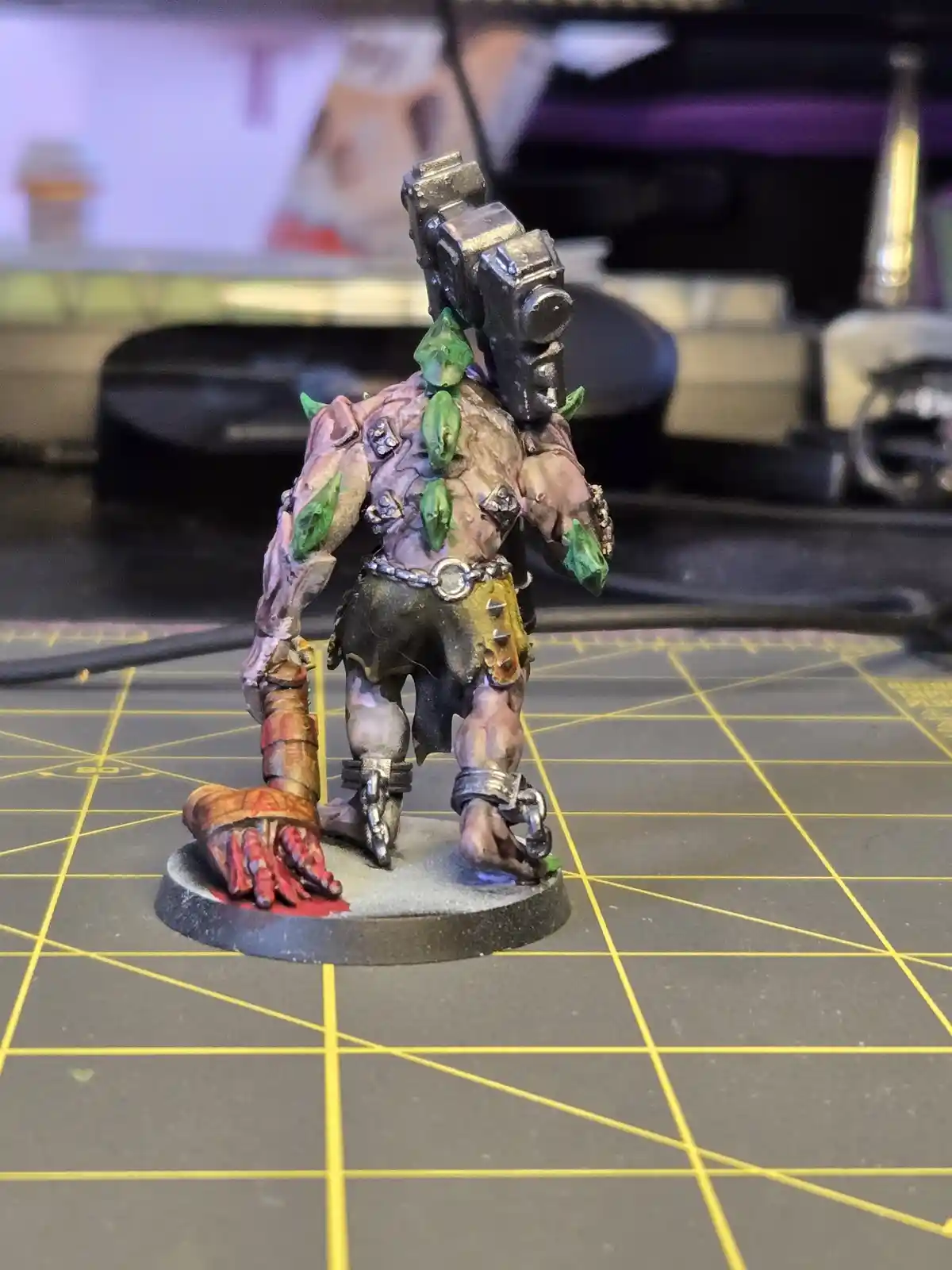 A heavily painted miniature figurine of a monstrous, muscular humanoid with green leaf-like growths on its back and arms…
