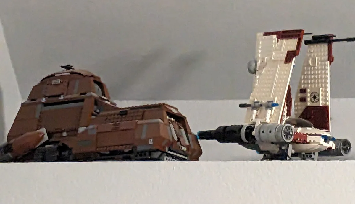 Two LEGO Star Wars vehicles are positioned on a white surface: a brown, heavily damaged-looking vehicle on the left and a…