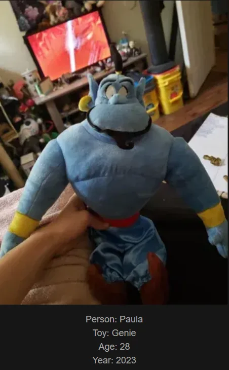 A person named Paula is holding a plush toy of the Genie from Aladdin, which is labeled as being 28 years old in 2023. The…