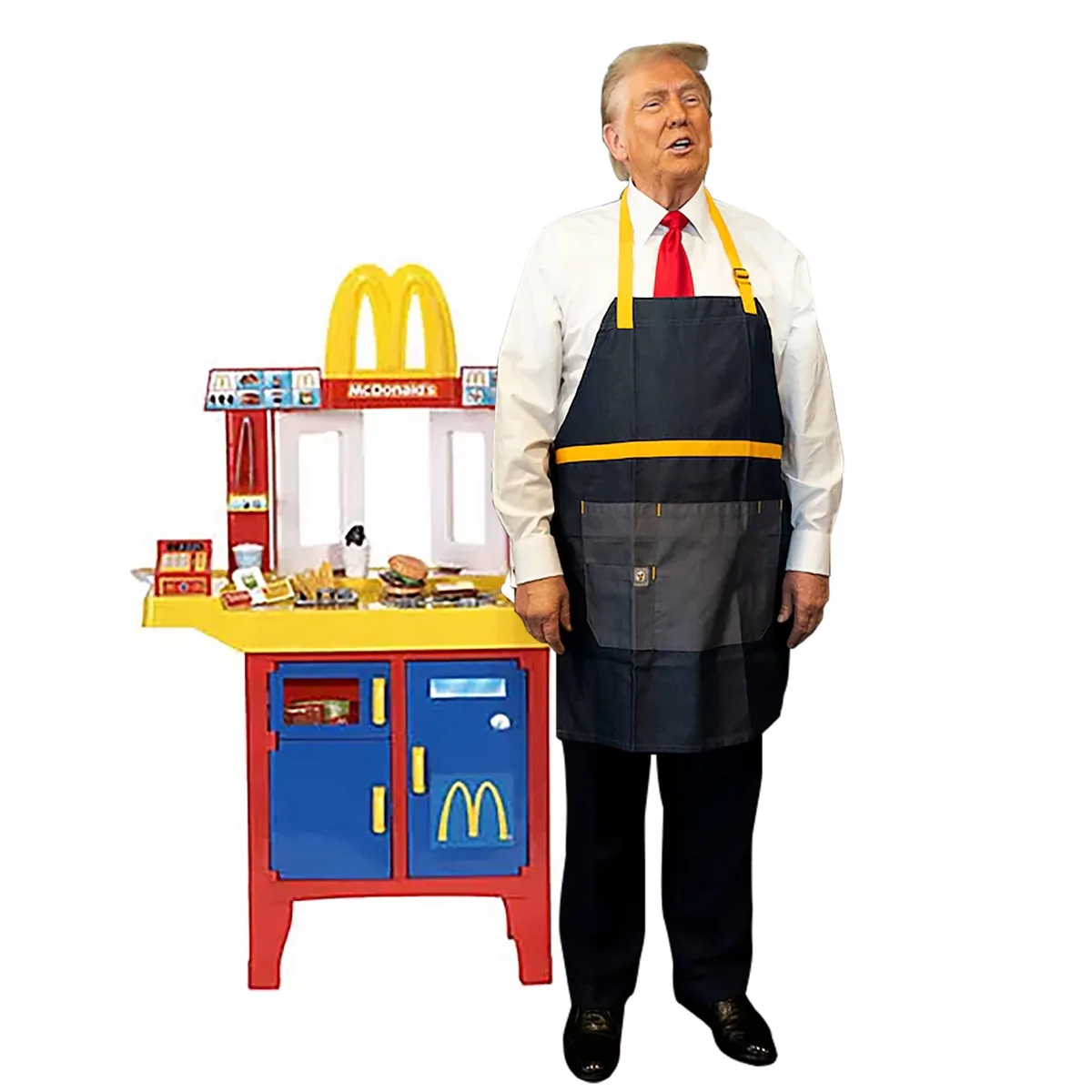 A man wearing a McDonald's employee apron stands beside a child's McDonald's playset. He is dressed in a white shirt, red…