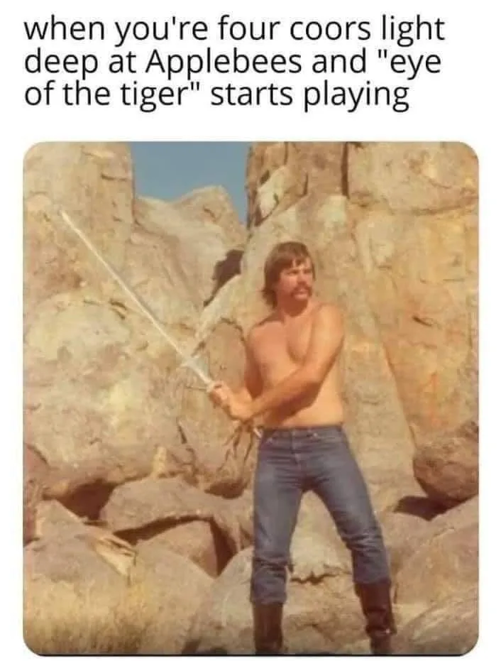 A shirtless man with a mustache stands in a rocky desert landscape, holding a sword in a heroic pose. The overlaid text…