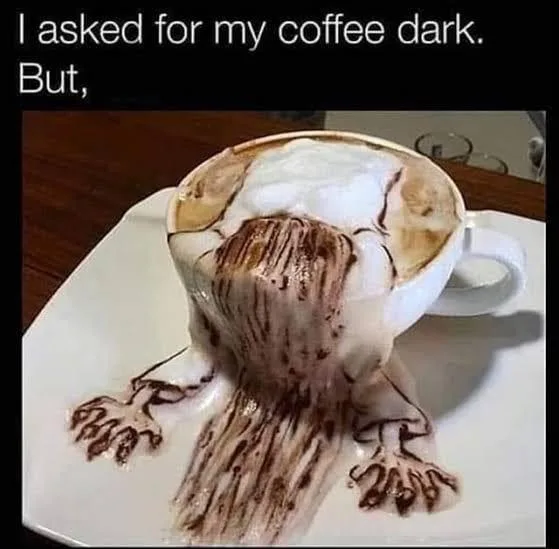 A white coffee cup sits on a white saucer, overflowing with coffee and foam that has been artistically drizzled to resemble…