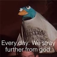 A close-up of a puppet resembling a duck with a blue head, orange beak, and white body, wearing a grey t-shirt with a faint…